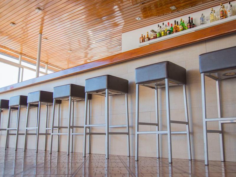 Bar moderno con taburetes altos alineados bajo una barra minimalista en un espacio luminoso.