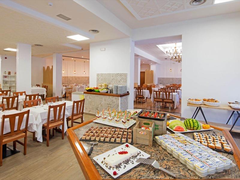 Área de buffet en un restaurante luminoso con mesas preparadas y variedad de alimentos.