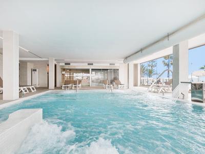 Moderner Innenpool mit Sprudelbad, großen Fenstern und weißen Liegen, helle freundliche Atmosphäre.