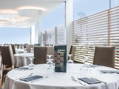 Elegant buitenrestaurant met moderne stoelen en tafel met glaswerk en menukaart bij daglicht.