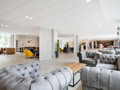 Heller, moderner Hotellobbybereich mit stilvollen grauen Sofas und einem Holztisch.