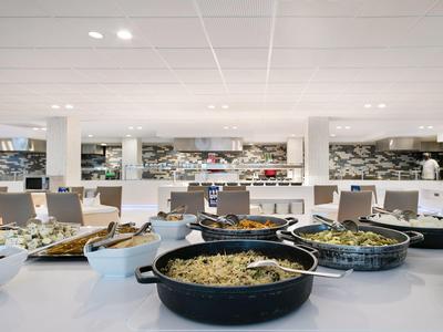 Buffet met verschillende warme en koude gerechten in een moderne restaurantomgeving.