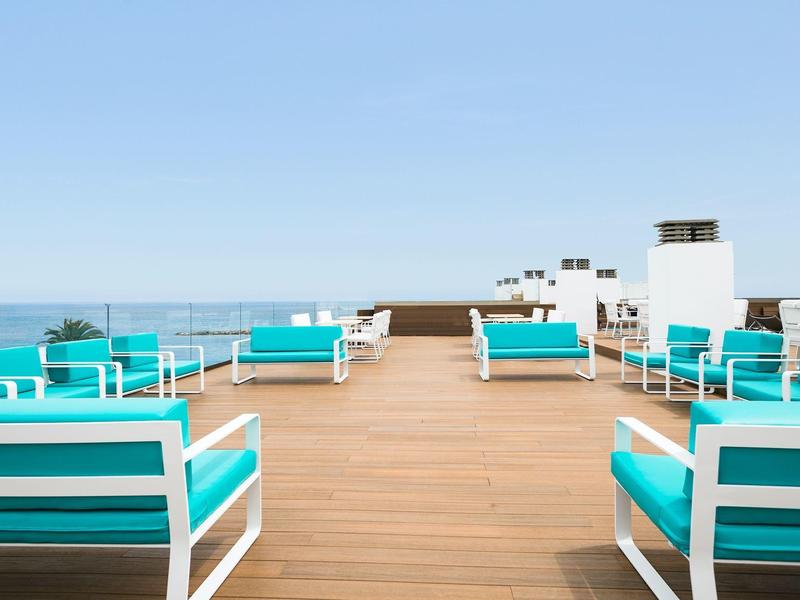 Open dakruimte met turquoise zitmeubilair en uitzicht op de oceaan