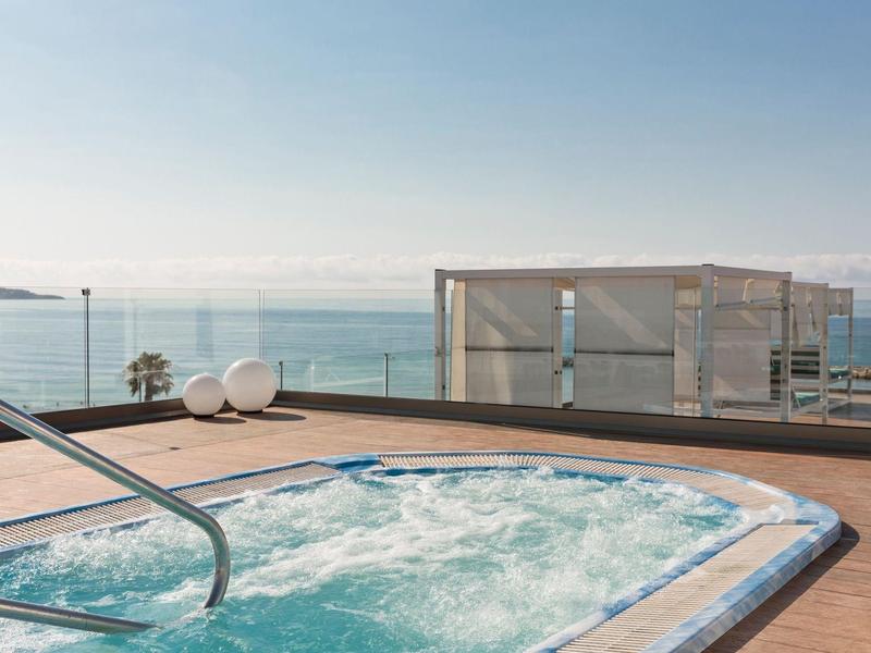 Bubbelbad op een terras met uitzicht op de zee onder een heldere blauwe lucht