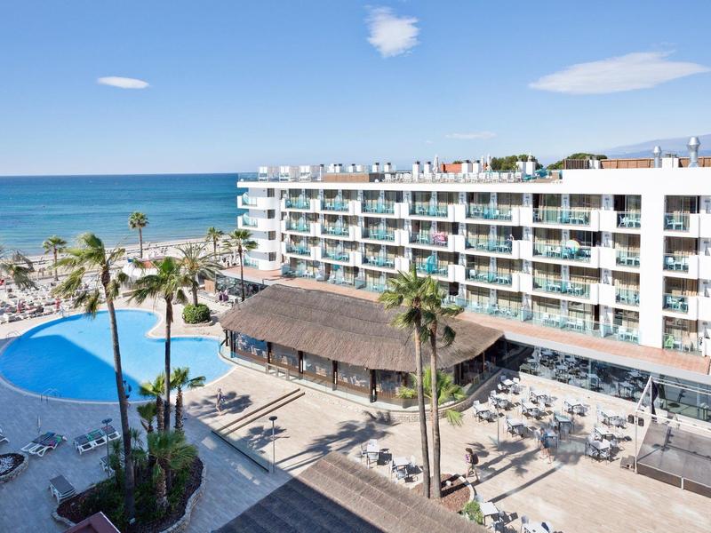 Hotel met zwembad, zeezicht en palmbomen op een zonnige kustlocatie