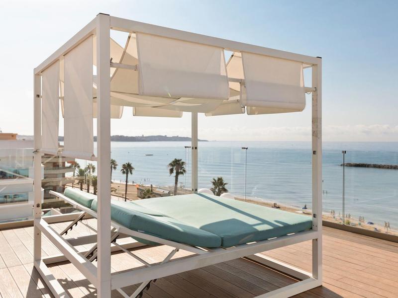 Modern daybed met zeezicht op een zonnig terras met glazen balkon.