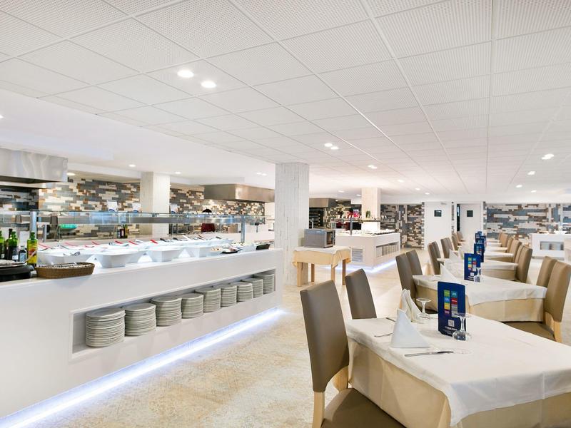 Licht, modern restaurant met gedekte tafels en een groot buffet.