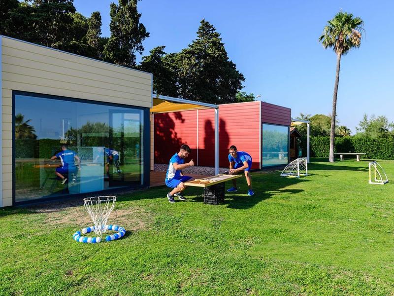 Modern small holiday cabins on green grass with people using a balance board.