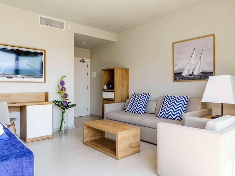 Bright living room with sofa, wooden table, TV, and nautical decor.