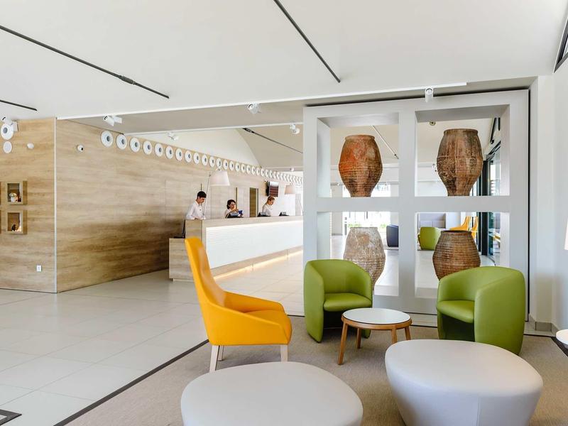 Modernly furnished hotel lounge area with colorful chairs and a reception desk in the background.