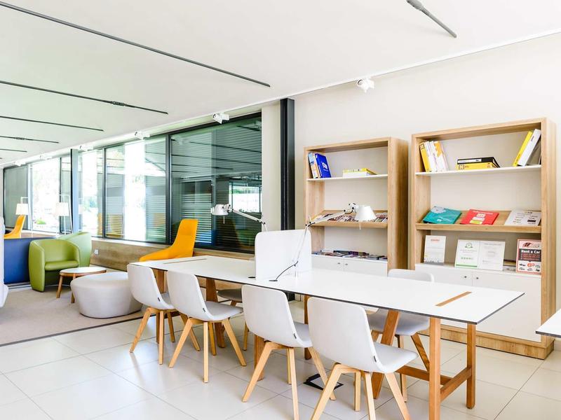 Modern meeting room with large table, white chairs, and bookshelves on the wall
