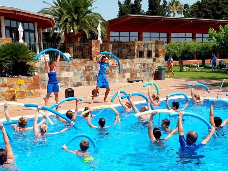 Children play and train synchronized in a hotel's pool under supervision.
