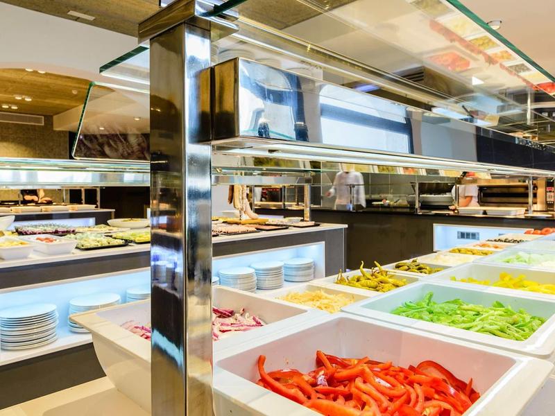 Buffet with various fresh salads and ingredients in a modern dining area.