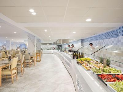 Comedor moderno de hotel con buffet y área de comedor en un espacio abierto y luminoso.