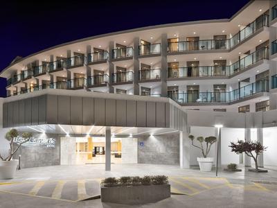 Edificio moderno de hotel de noche con entrada iluminada y balcones.