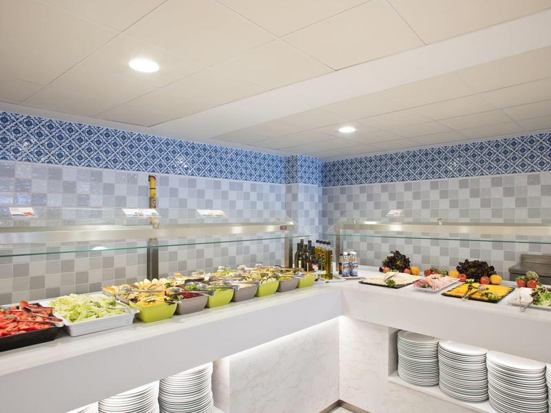 Buffet con varias frutas frescas y comidas en una sala moderna y bien iluminada.