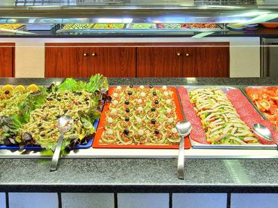 Salatbuffet mit verschiedenen frischen Gemüsesorten und Salaten in Edelstahlbehältern.