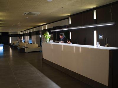 Moderner Empfangsbereich mit langer weißer Theke, dunklen Wänden und gedämpfter Beleuchtung.