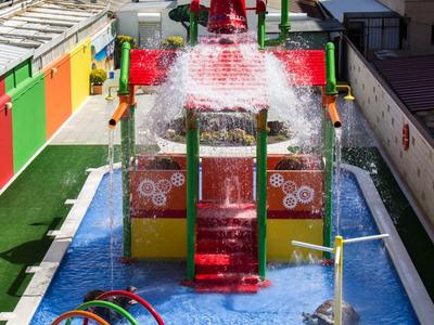 Colorful water playground with slides and water fountains in a hotel pool area.