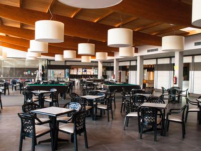 Large dining area with black chairs and wooden beam ceiling in a hotel.