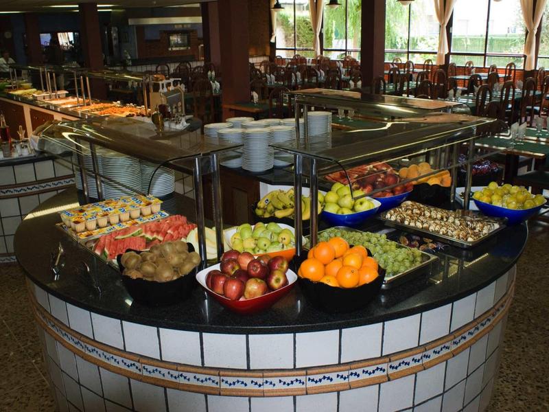 Buffet mit Obstschalen in rundem, weiß gekacheltem Bistro-Inseltisch, dunkles Holz und große Fenster.