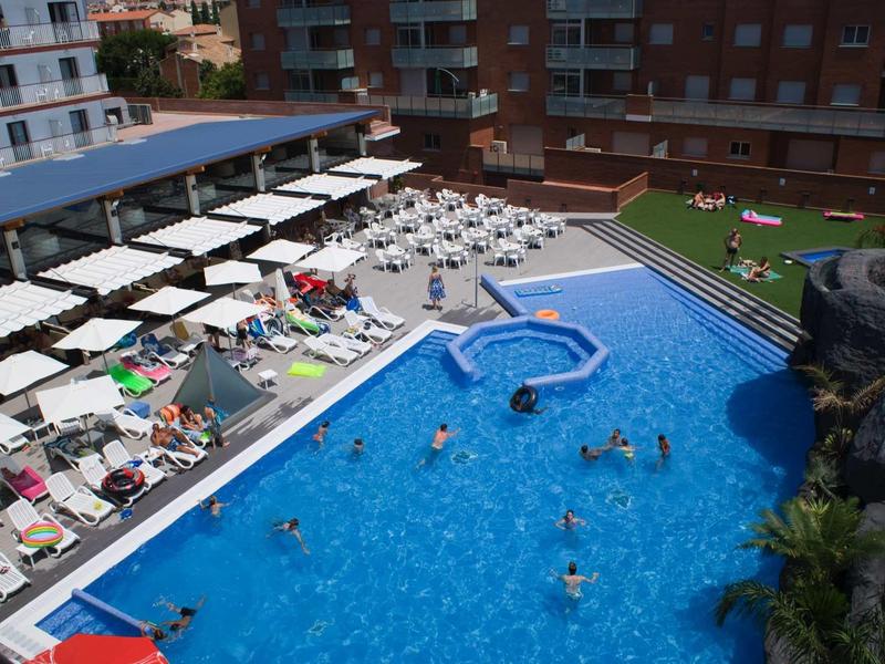 Großer rechteckiger Pool mit Kindern, Liegestühlen und Sonnenschirmen in Wohnanlage.