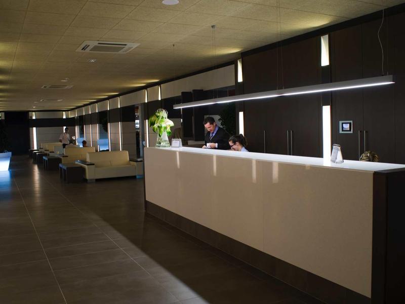 Moderner Empfangsbereich mit langer weißer Theke, dunklen Wänden und gedämpfter Beleuchtung.