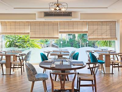 Heller, moderner Essbereich mit runden Holztischen, gemusterten Stühlen und großen Fenstern.