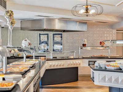 Modernes Buffet mit vielfältigen Speisen, hellem Ambiente und klaren Glasvitrinen in warmem Licht.