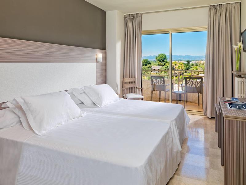 Jasny pokój hotelowy z dwoma pojedynczymi łóżkami, balkonem i malowniczym widokiem.