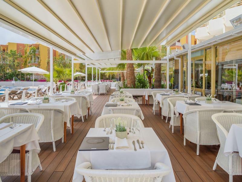 Restauracja na zewnątrz z białymi obrusami i krzesłami pod rozkładanym dachem.