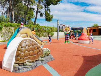 Dzieci bawiące się na kolorowym placu zabaw z dinozaurami na słonecznym świeżym powietrzu.