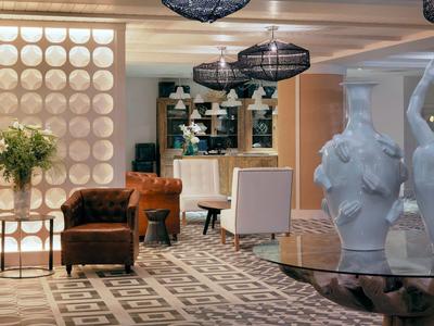 Lobby d'hôtel élégant avec fauteuils, grandes vases blancs et luminaires modernes.