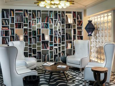 Salon élégant d'hôtel avec fauteuils et grande bibliothèque moderne.
