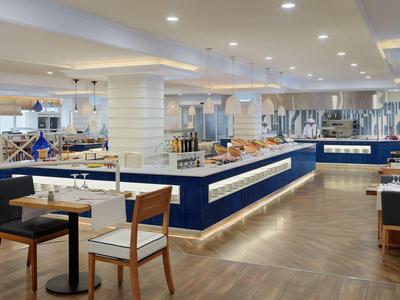 Restaurant moderne avec tables, chaises et buffet lumineux dans un espace spacieux.