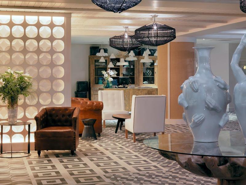 Lobby d'hôtel élégant avec fauteuils, grandes vases blancs et luminaires modernes.