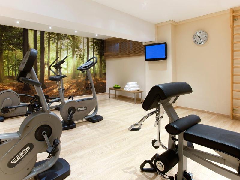 Salle de sport moderne avec vélos d'appartement et équipements de musculation en bois clair.