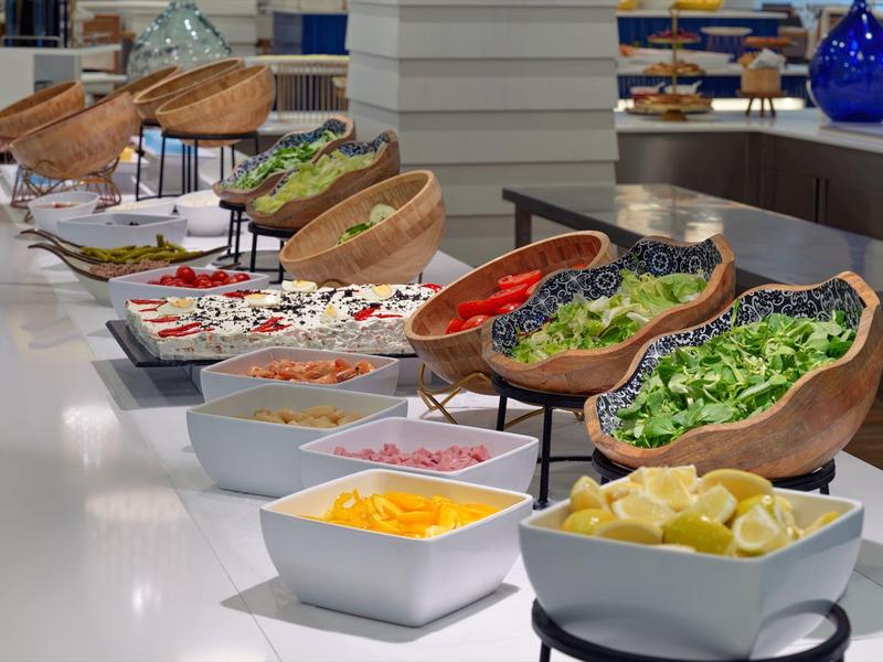 Buffet élégant avec salades fraîches colorées dans des plats en bois et des bols blancs.