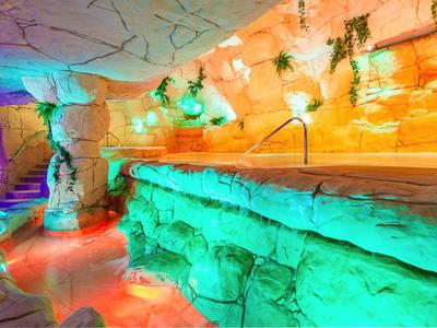 Interiér hotelu s osvětlenými kamennými zdmi a bazénem s madlem.