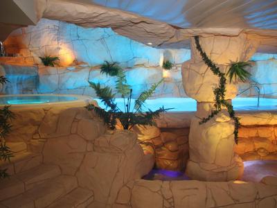 Vnitřní bazén s kamennými stěnami a exotickou výzdobou v relaxační hotelové atmosféře.