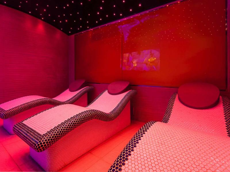 Relaxacní prostor s elegantními lehátky a cerveným osvetlením v lázních.