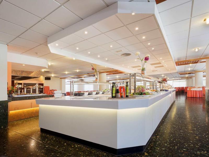 Moderní hotelový bar se osvětleným pultem a červeným posezením v jasné místnosti.