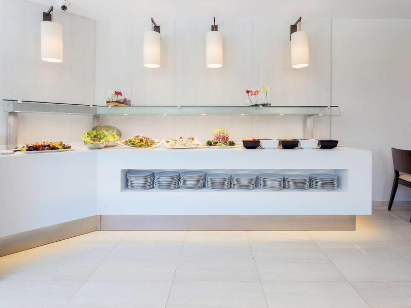 Minimalistická snídaňová oblast s osvětleným bufetem a úhledně uspořádaným nádobím.