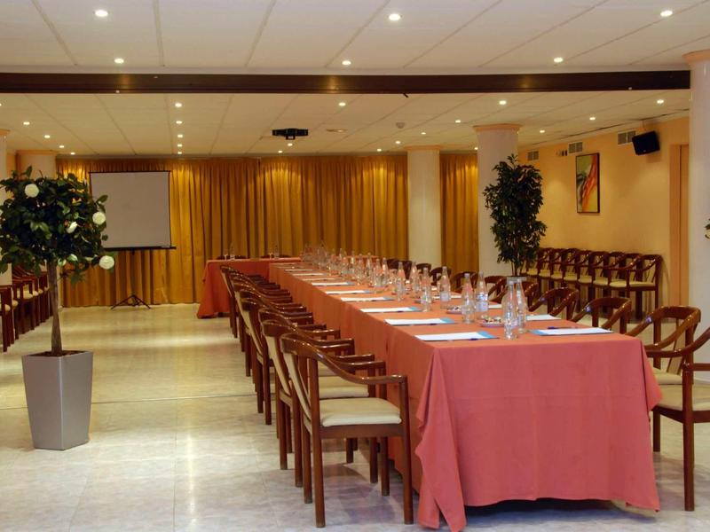 Konferenční místnost s dlouhým stolem, červeným ubrusem, židlemi a stropním osvětlením