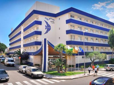 Edificio de hotel moderno de varios pisos con acentos azules y tráfico circundante.