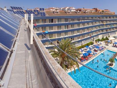 Hotel con paneles solares, área de piscina y tumbonas en día soleado.
