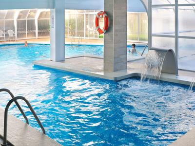 Piscina interior con cascada de agua y salvavidas en una columna