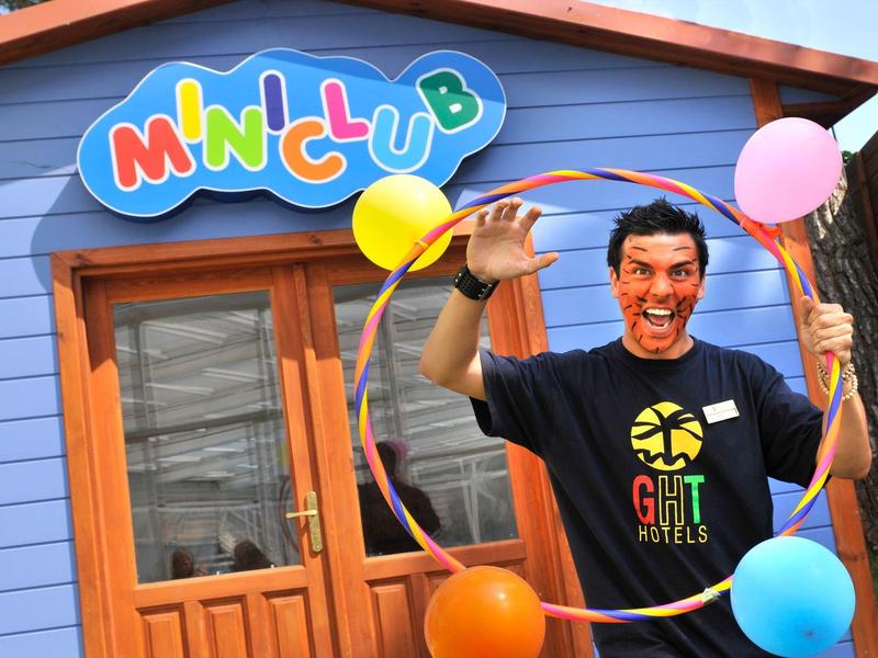 Empleado feliz frente a un edificio colorido con globos y un aro