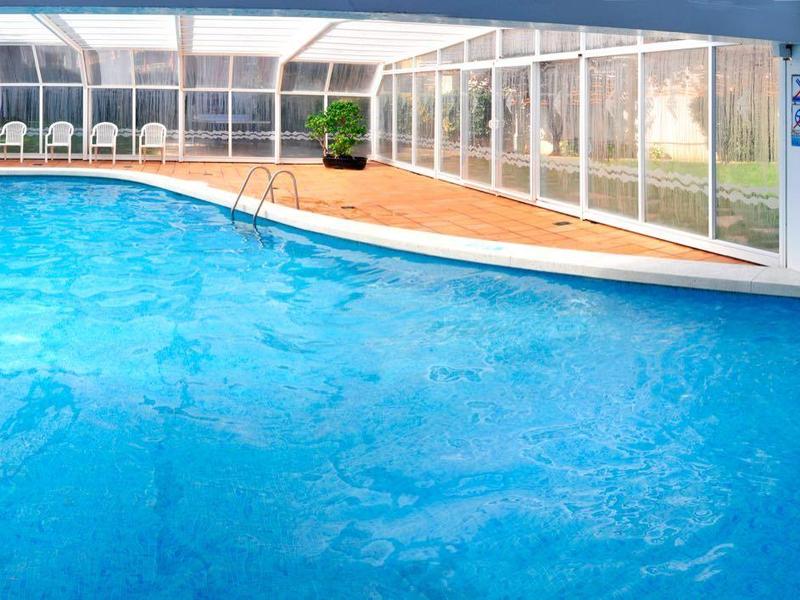 Piscina interior moderna con muro de vidrio y jacuzzi integrado en espacio luminoso