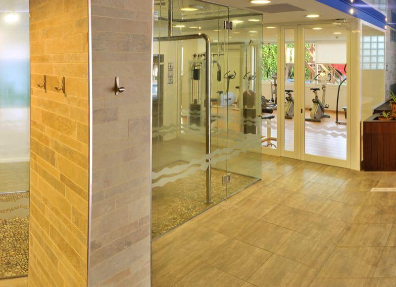 Área de spa moderna con paredes de vidrio, sauna y suelo de madera clara en un hotel.